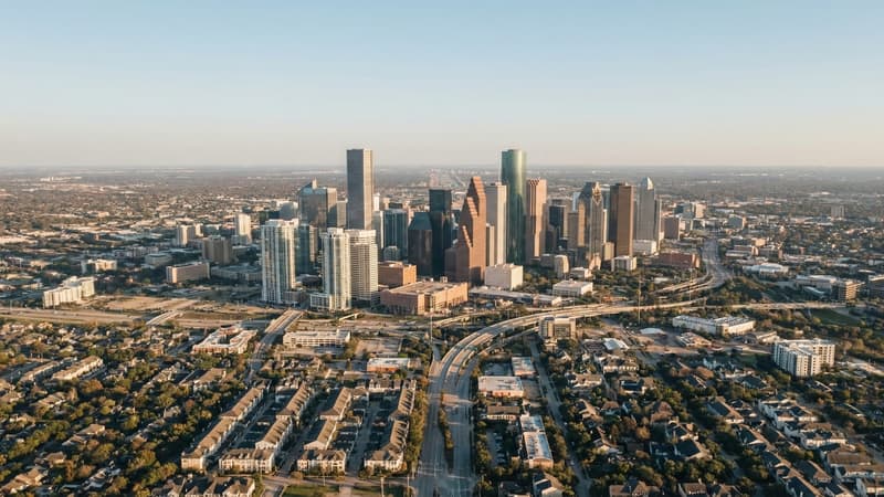 Aerial view of the Houston, Texas skyline and vast surrounding residential neighborhoods extending toward the horizon, illustrating the city's expansive housing supply