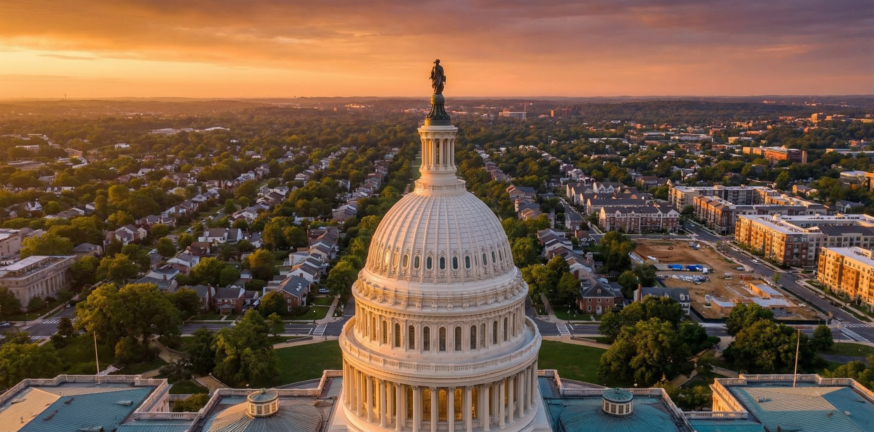 Aerial view of the U.S. Capitol building with a suburban residential neighborhood stretching toward the horizon under dramatic morning sky