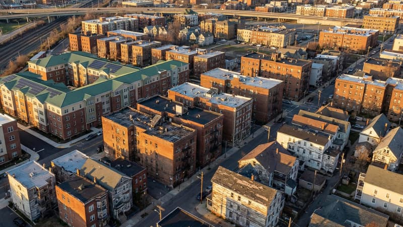 Aerial view of dense urban rental housing complex showing varied quality apartment buildings in an American city