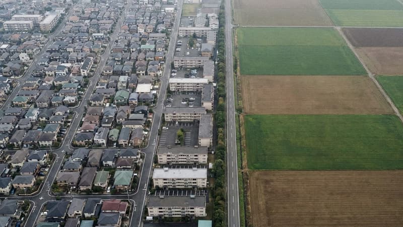 Aerial view of a dense urban district with compact housing blocks meeting open farmland at a sharp boundary line